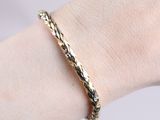 the woman is wearing a gold bracelet that has a braid design on it