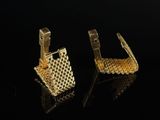 a pair of gold earrings on a black surface