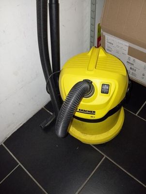 un aspirateur jaune posé par terre à côté d'un carton