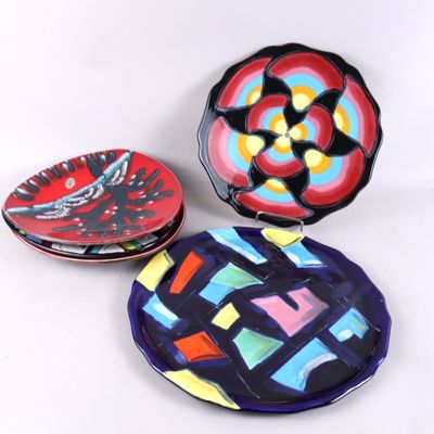 trois assiettes colorées ornées de motifs, posées sur une surface blanche