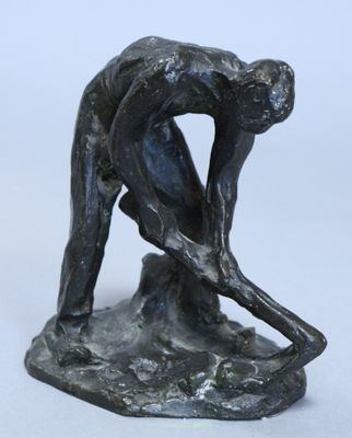 statue représentant un homme penché en avant pour ramasser quelque chose par terre