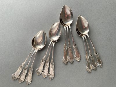 six spoons and a spoon rest on a gray surface