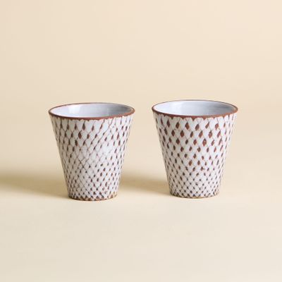 une paire de tasses en céramique blanches et marron sur fond beige
