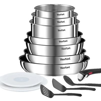 une pile de casseroles et de poêles en inox à côté d'un couteau et d'une fourchette