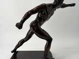 bronze statue of a man in a running pose on a marble base