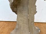 une photo représentant une sculpture représentant une tête, posée sur une table en bois