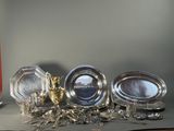 three silver dishes on a table next to a candle