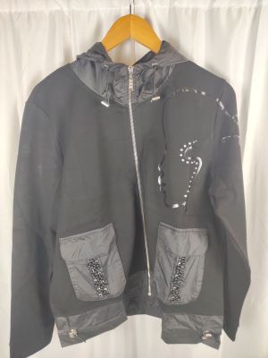 veste Nike grise à capuche et fermetures éclair, suspendue à un cintre devant un rideau blanc