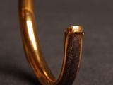 close up of a gold ring with a brown leather band