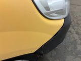 the front end of a yellow car with a dent in it