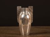 a silver vase sitting on a wooden table with a black background