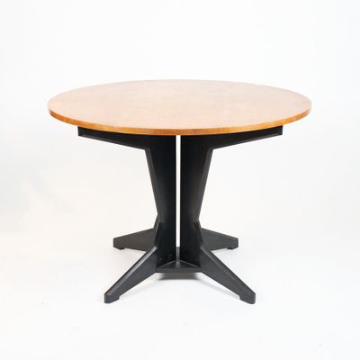 une table ronde en bois avec des pieds noirs et un plateau en bois