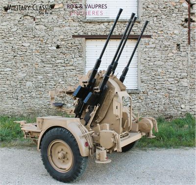 a military vehicle with two guns on it parked in front of a building