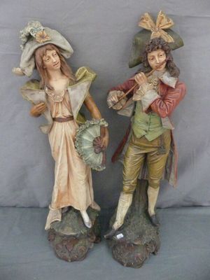 deux figurines représentant un homme et une femme portant un chapeau et une queue-de-pie