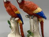 deux figurines représentant des perroquets perchés sur une souche d'arbre