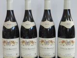 four bottles of wine are lined up on a white surface