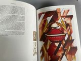 an open book with a picture of a red perfume bottle on it
