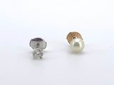 une paire de boucles d'oreilles clous ornées de diamants et de perles, sur fond blanc