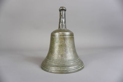une clochette argentée posée sur une surface blanche