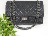 un sac Chanel noir avec une bandoulière en chaîne et une fleur