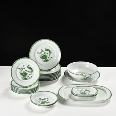 des assiettes et des bols verts et blancs posés sur une table blanche, sur fond noir