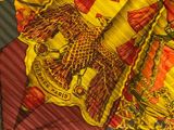 a close up of a yellow and red scarf with a bird on it