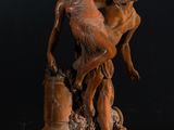 a statue of a man holding a woman on top of a wooden base