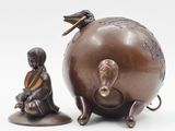 a statue of a man sitting on a stool next to a globe