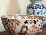 a bowl sitting on a table next to a vase on a shelf