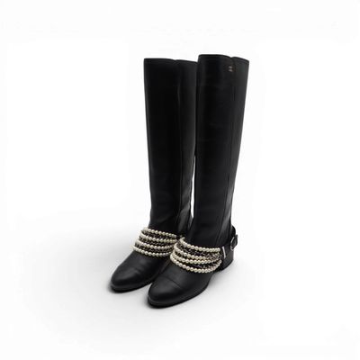 une paire de bottes en cuir noir ornées de perles et de chaînes