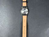 a watch on a black surface with a brown strap