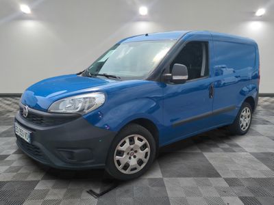 Une camionnette bleue est garée dans une pièce au sol à carreaux.