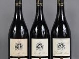 three bottles of wine are lined up on a table