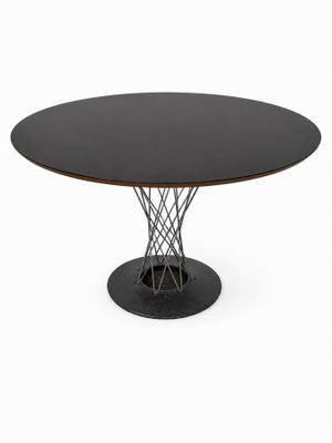 une table ronde avec un plateau noir et un piètement en métal