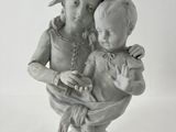 une statue représentant une femme tenant un enfant dans un bol