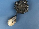 an antique silver broochle with a pearl and a diamond