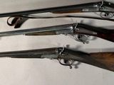several different types of guns mounted on a wall in a room
