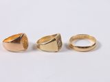 three different types of gold rings on a white surface