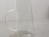 a glass pitcher with a wooden lid sitting on a table