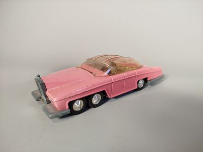 une petite voiture rose posée sur une surface blanche