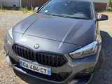 the front view of a grey bmw car parked in front of a building