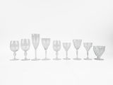 nine wine glasses lined up in a row on a white surface
