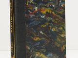 un vieux livre à la couverture noire posé sur une table blanche