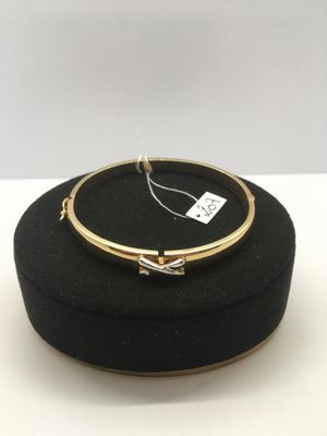 un gros plan d'un bracelet en or posé sur un chapeau noir