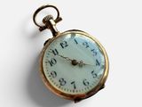 a gold pocket watch with a white face on a white surface