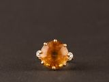 un gros plan d'une bague sertie d'un saphir jaune sur une surface noire