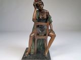 statue en bronze représentant une femme assise sur une chaise, un panier sur la tête