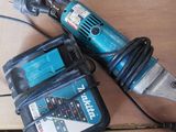 une perceuse filaire et deux batteries posées sur une table en bois