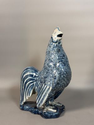 une figurine de coq bleue et blanche posée sur une table