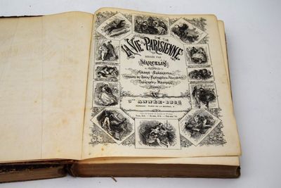 Un vieux livre est ouvert sur une surface blanche ornée d'illustrations.
